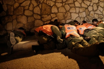 Israeli soldiers taking cover as an air raid siren warns of incoming rockets before the funeral of Aaron Smadja, one of the three Israelis killed by a rocket fired from Gaza, at a cemetery in the southern city of Kiryat Malachi, Nov.15, 2012.  (Tsafrir Abayov/Flash90)