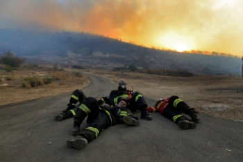 Firefighters rest on the road at sunrise after struggling to gain
control over the massive wildfire in the Carmel Forest, Dec. 3, 2010.
Photo by Tsafrir Abayov/Flash90
 (Tsafrir Abayov/Flash 90)