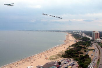 A small airplane flying above Punte del Este with a sign that reads "Shabbat Shalom" and the time Shabbat begins. (Courtesy Jabad Lubavitch Punta del Este)