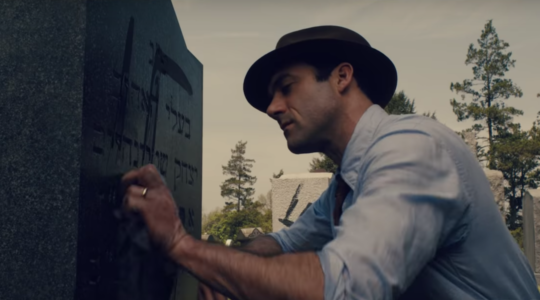 Morgan Spector, as Herman in the trailer for HBO's "The Plot Against America," cleans a swastika off of a Jewish gravestone. (Screen shot from YouTube)