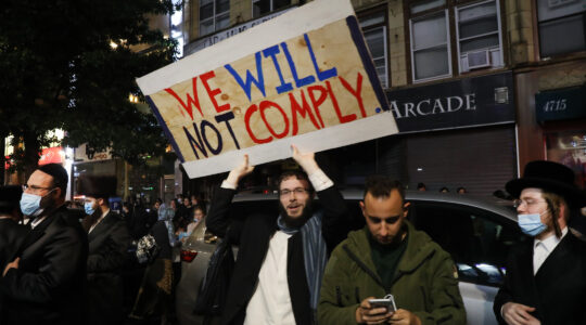 A man holds up a sign reading "We will not comply" during recent protests in Borough Park against public health restrictions on October 7. (Spencer Platt/Getty Images)