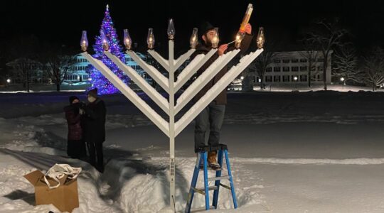 Rabbi Moshe Gray lights the Dartmouth campus menorah the night after he discovered that it had been shot through with a pellet gun. The menorah can still be lit with fire despite the vandalism. (Courtesy of Gray)