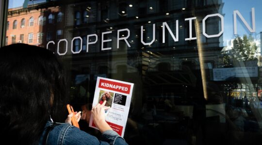 A woman affixes a flier for Israeli hostages to Cooper Union college in New York City, a day after Jewish students sheltered in a library during a pro-Palestinian protest, Oct. 26, 2023. (Luke Tress)