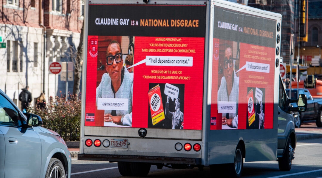 A truck reading "Claudine Gay is a National Disgrace," next to photos of Gay and Hitler, drives through Harvard's campus