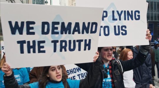 Jewish activists march with signs reading "We Demand The Truth" and "Stop Lying To Us"