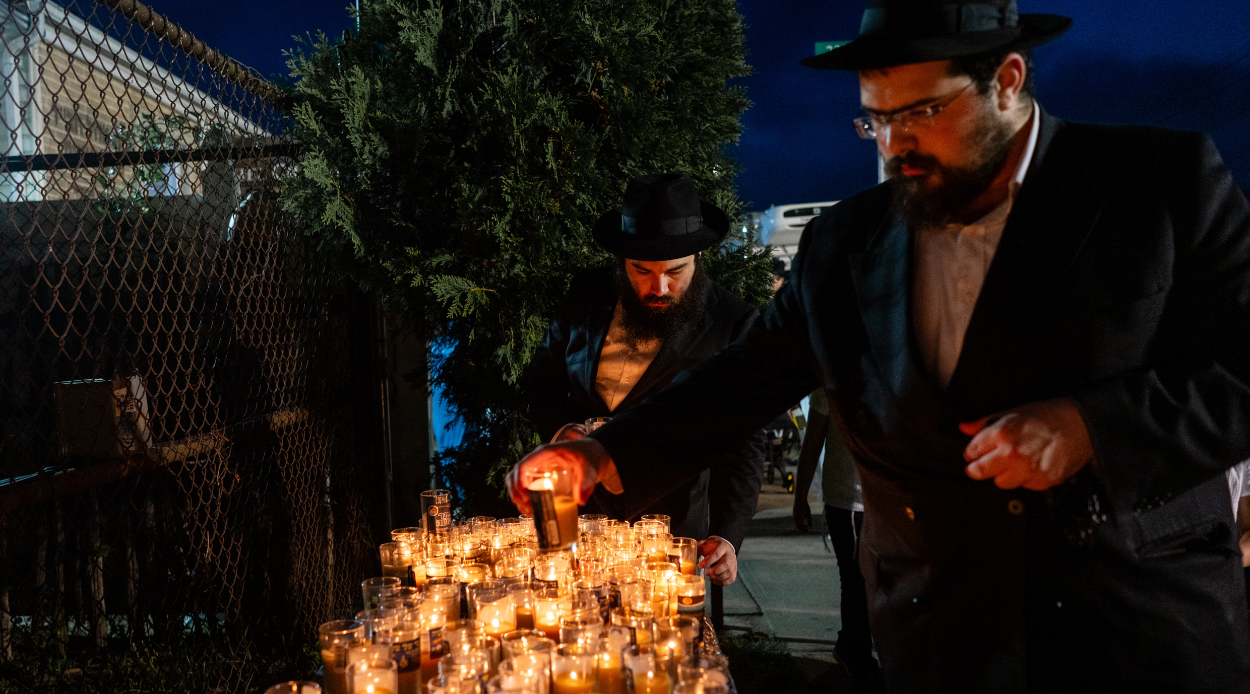 Lighting candles outside the resting place of Rabbi Menachem Mendel Schneerson, the Lubavitcher rebbe, on the 30th anniversary of his passing, in Queens, July 8, 2024. (Luke Tress)