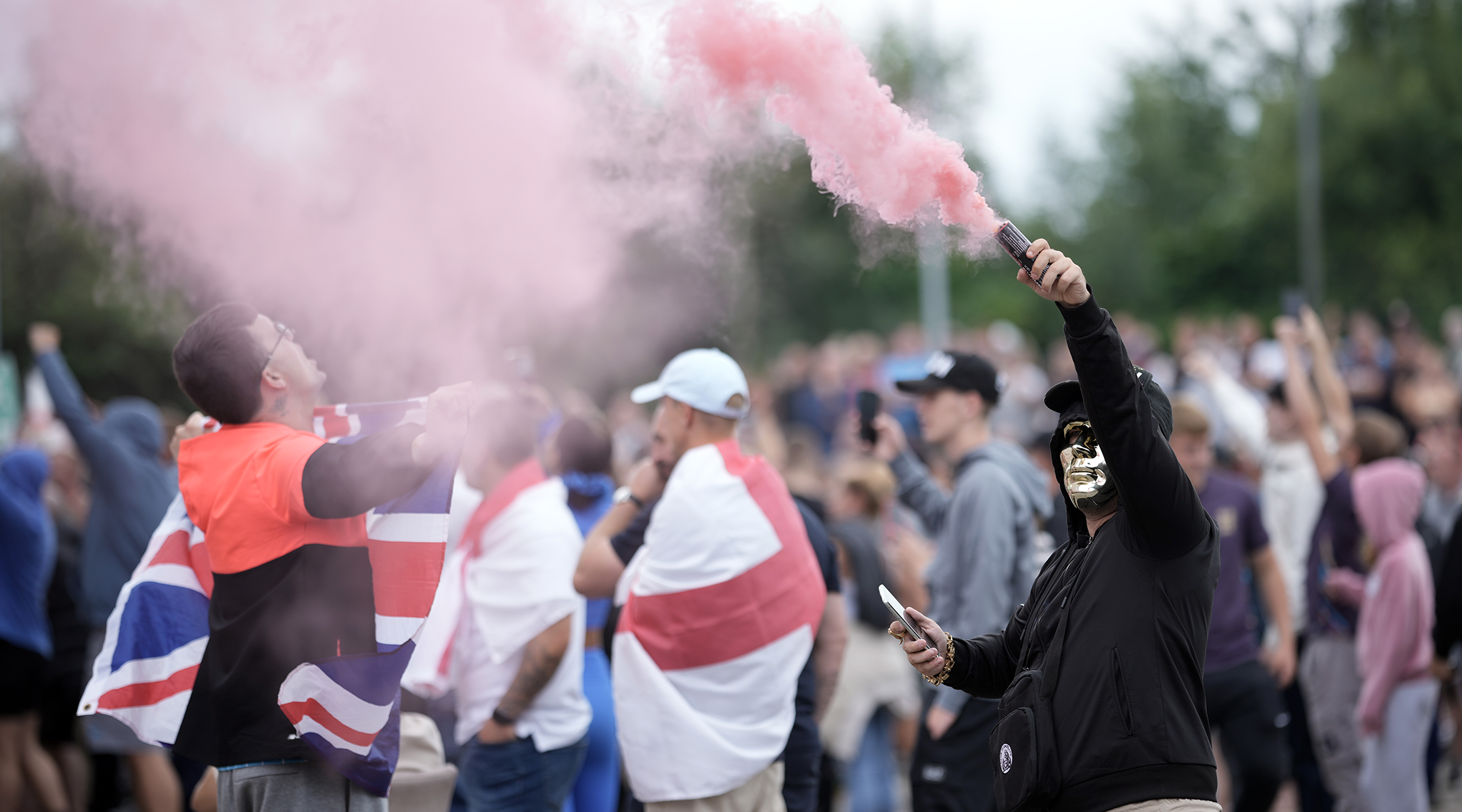 An anti-migration protestor holds a flare during a riot.