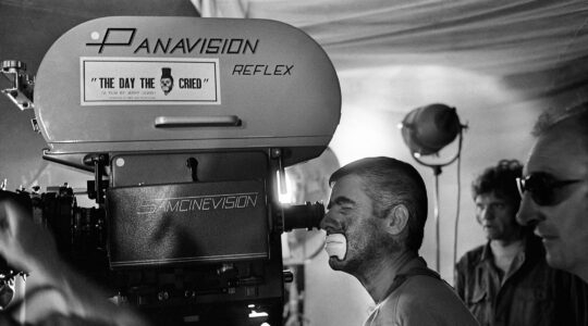 Jerry Lewis in clown makeup looks through a camera on a movie set