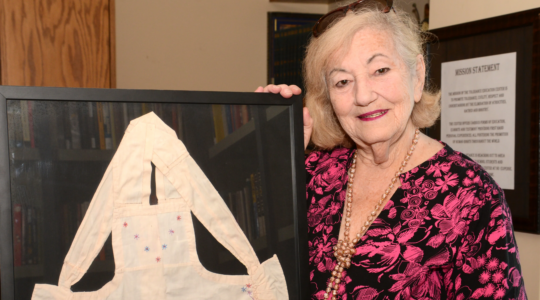 Holocaust survivor Goldie Jacoby holds an apron her mother made for her 6th birthday while the family was hiding in a barn to survive the Holocaust. (Courtesy/Blue Card)