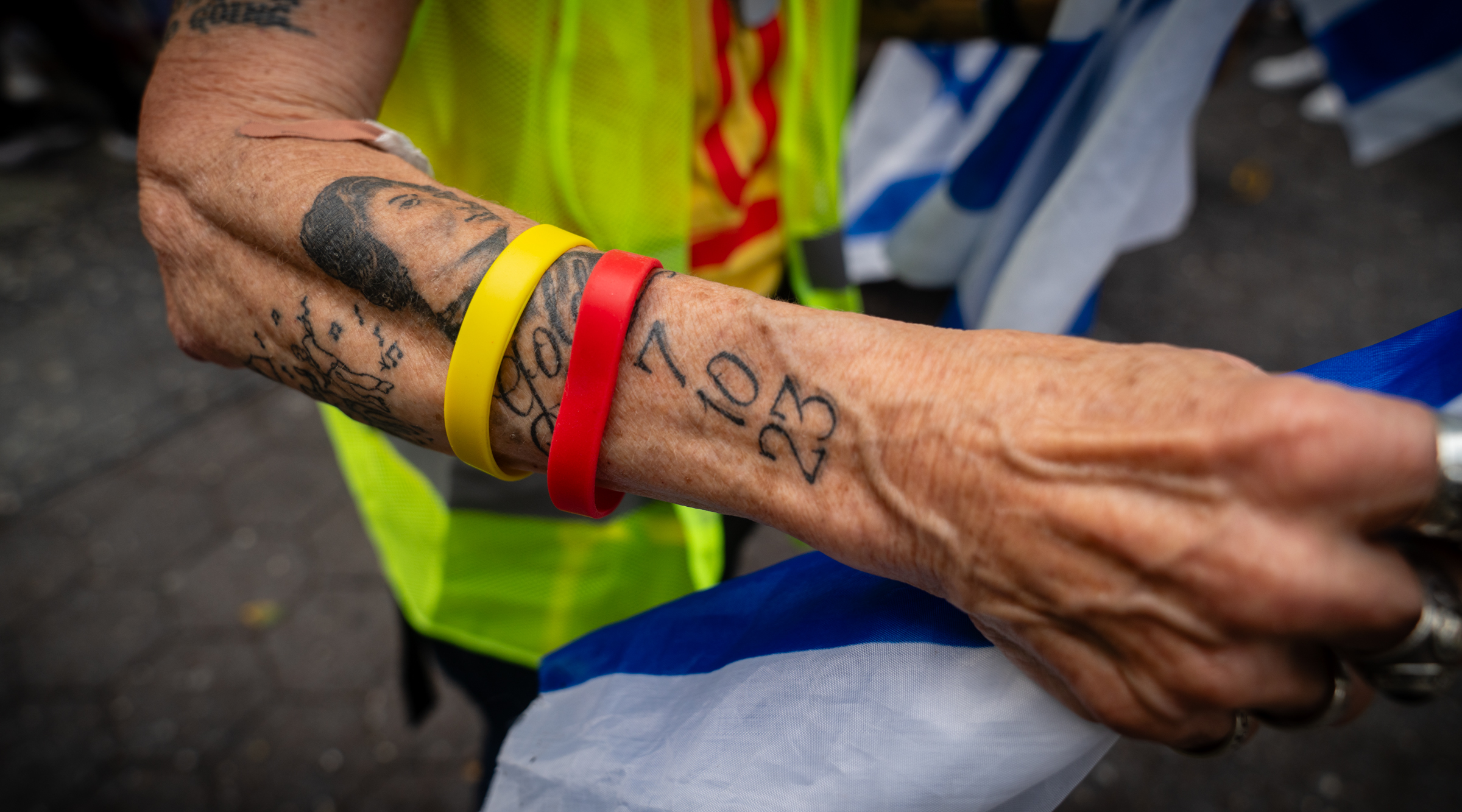 A volunteer with the Hostages and Missing Families Forum shows a tattoo commemorating the Oct. 7 attack at a rally for the hostages in midtown Manhattan. Volunteers handed out stickers with the number "351," marking the number of days since the captives were taken. Sept. 20, 2024. (Luke Tress)