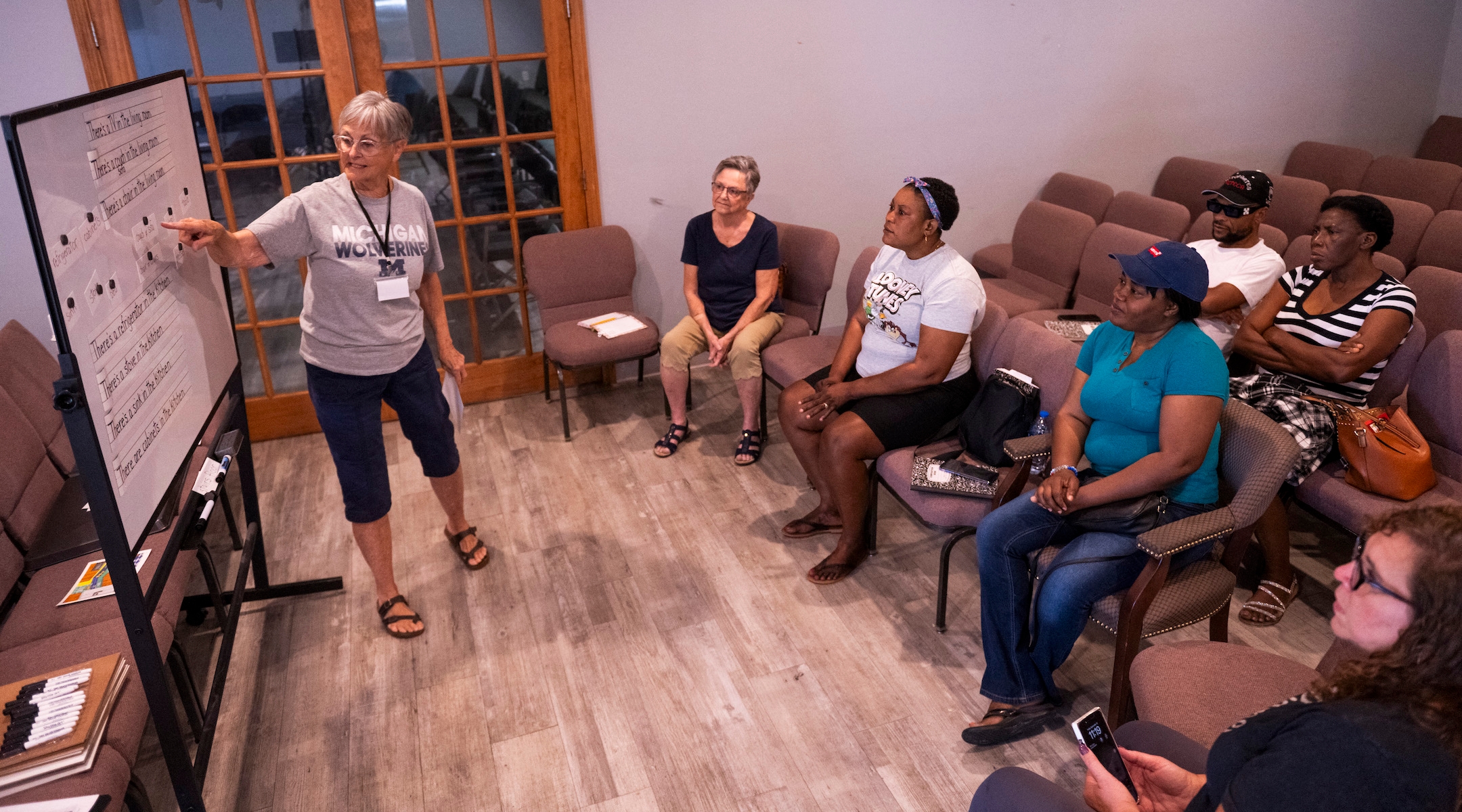 A woman leading an adult English class for mostly Haitian students