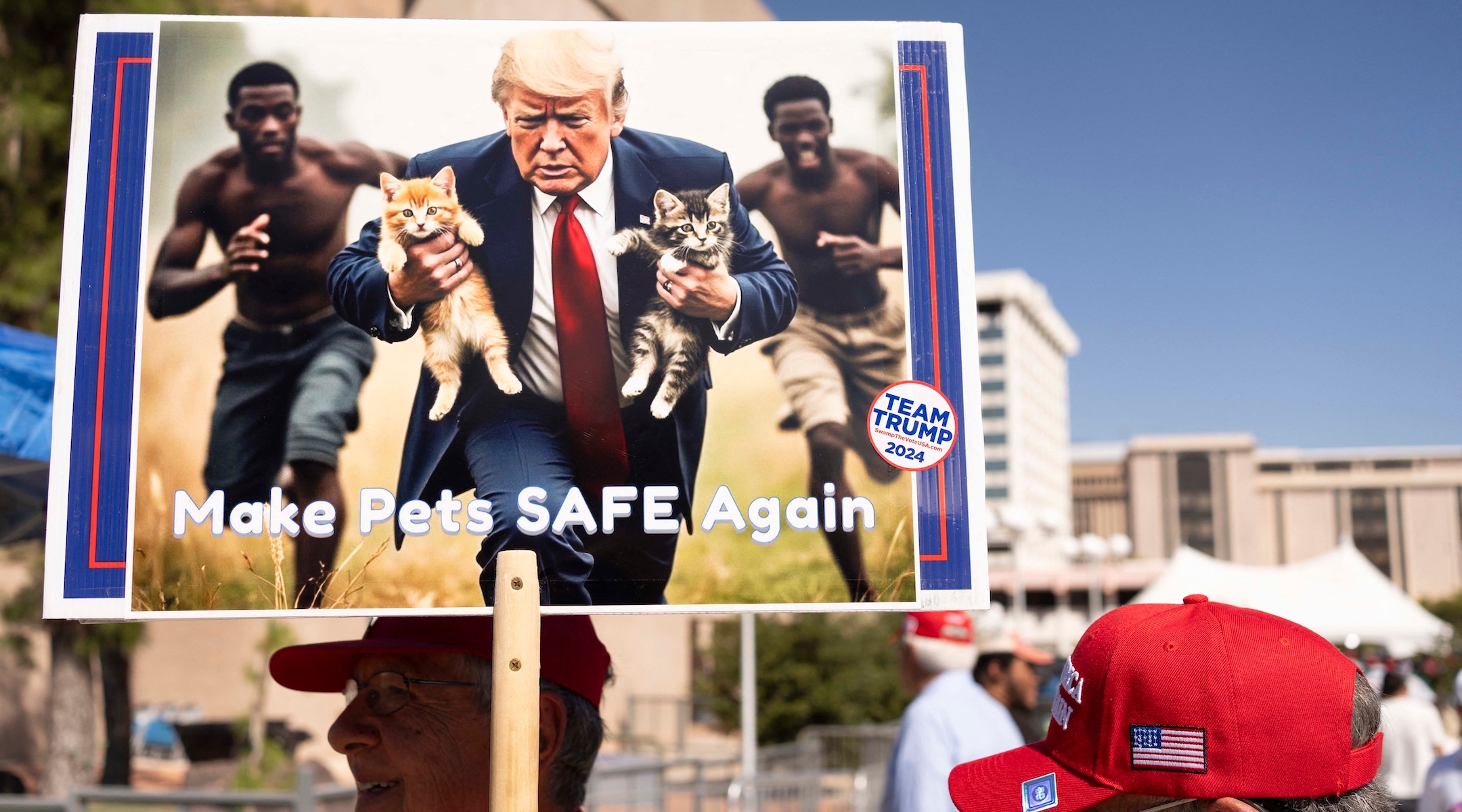 A man holds a large poster of an AI-generated image of Donald Trump rescuing cats from Haitians