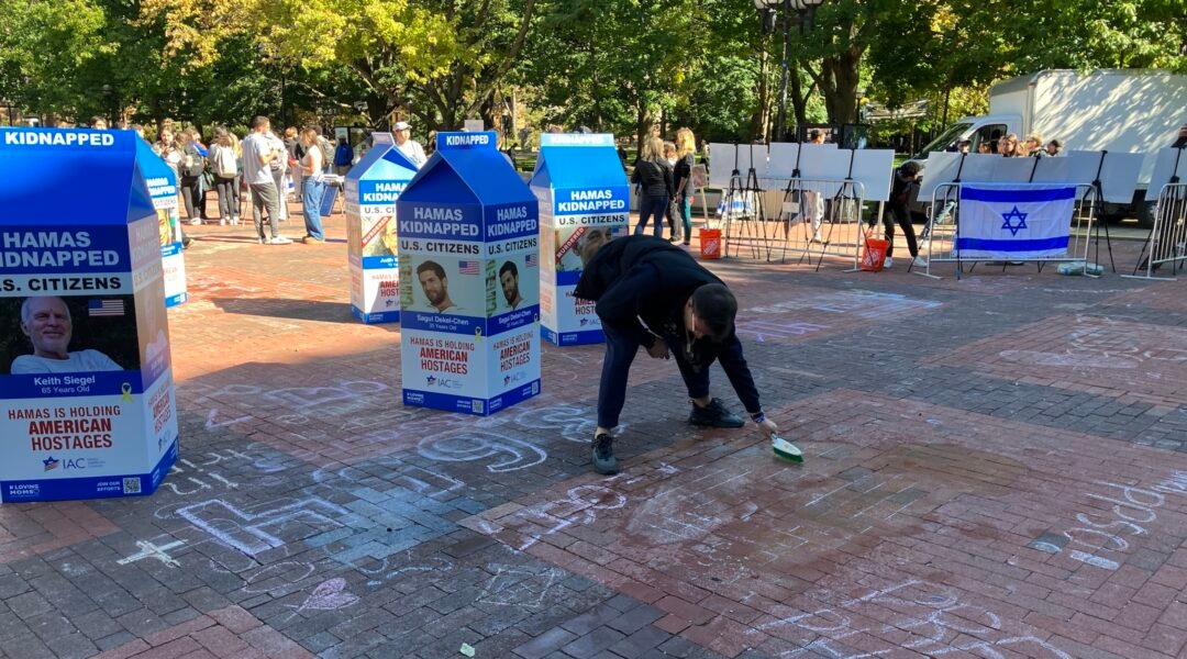 A Jewish student removing a chalk message at a college campus Oct 7 memorial