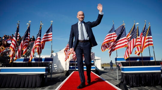 Stephen Miller waving on a runway surrounded by American flags