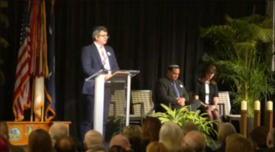 A rabbi stands at a podium during a Holocaust memorial event