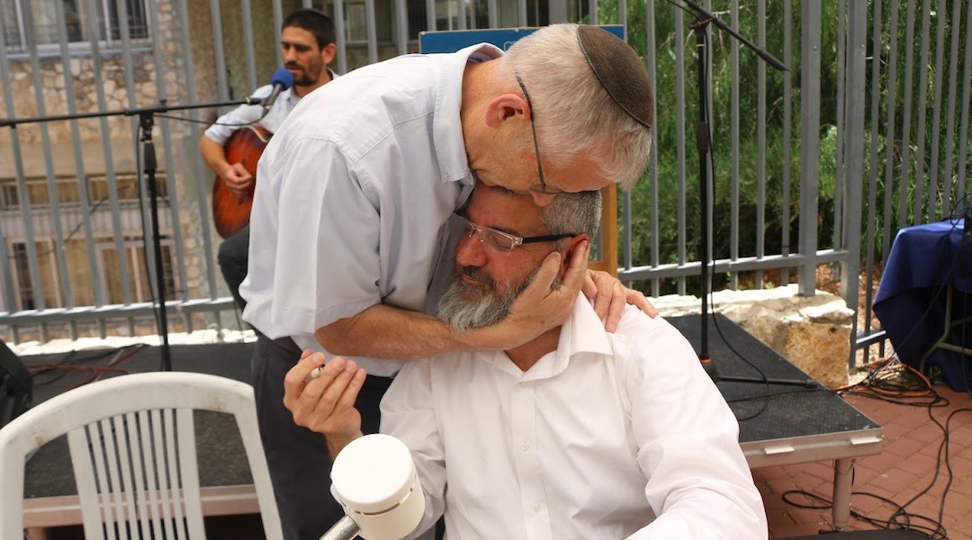 Rabbi Jeremy Stavisky hugs a teacher and scribe who wrote a Torah scroll in honor of the fallen alumni. (Courtesy of Himmelfarb)