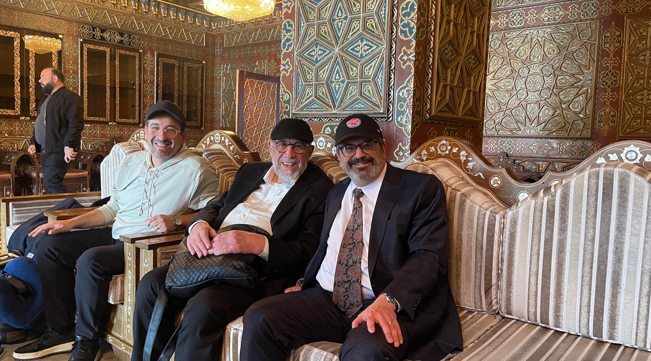 Three Jewish men sit in the ornate lobby of a hotel in Syria