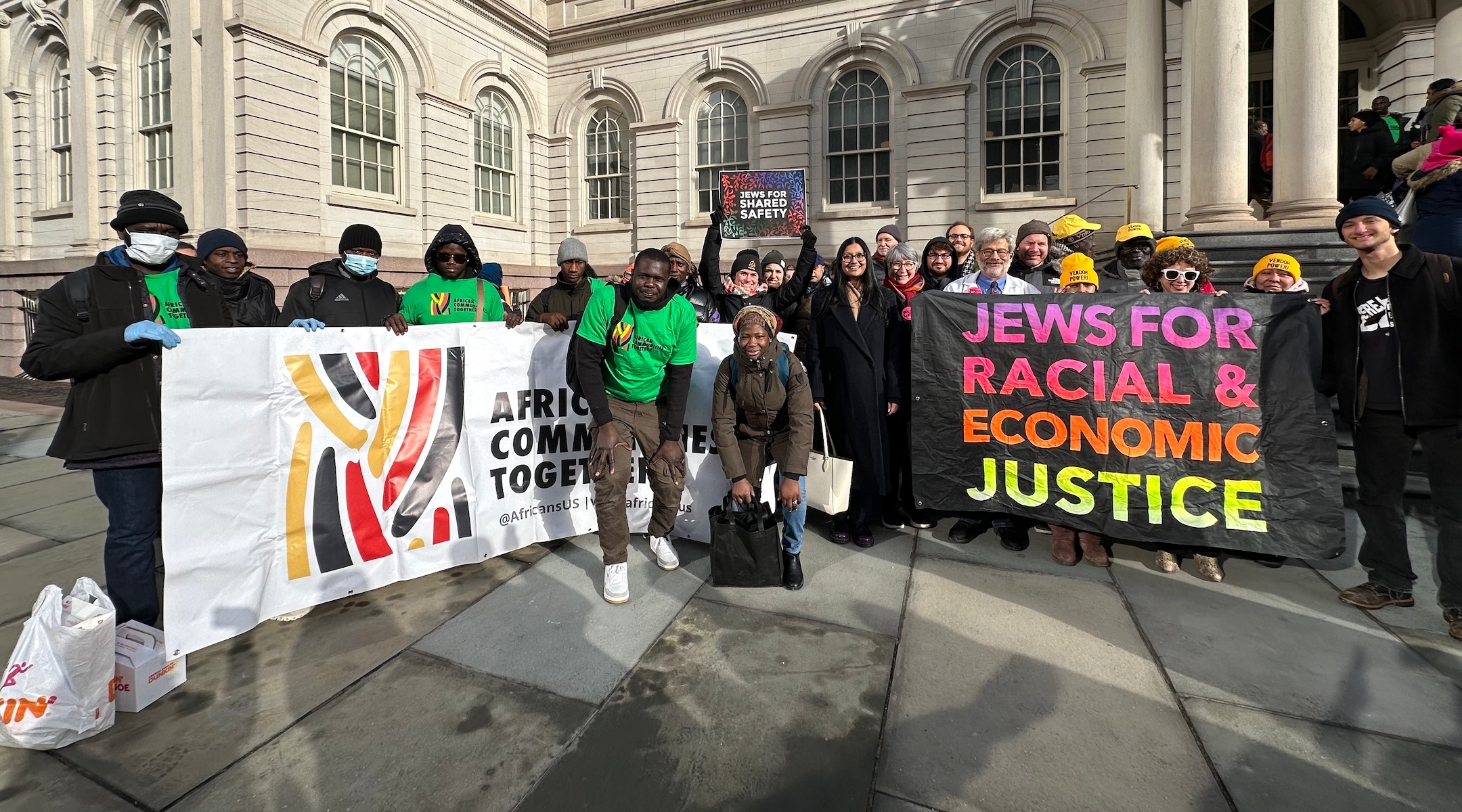 Activists hold signs outside of a city hall building